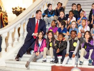 Bob Beard sitting on Capitol steps with kids from RIF program