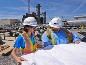 two ugi employees looking at diagram in the working field surrounded by pipelines