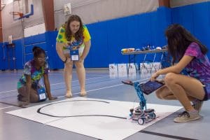 Three STEM campers navigate their robot through a pattern