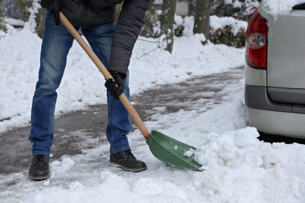 person shoveling snow away from vehicle