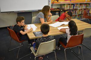 Students sitting at a table working on their plays