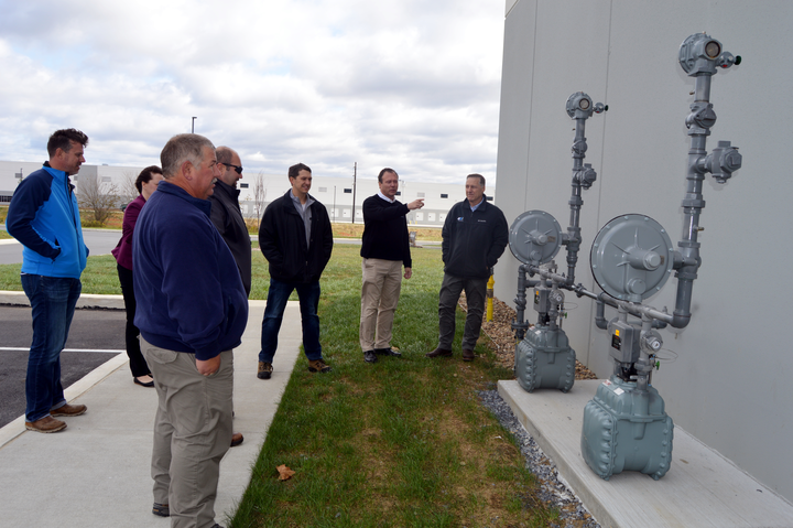 a group of men standing around two large natural gas meters