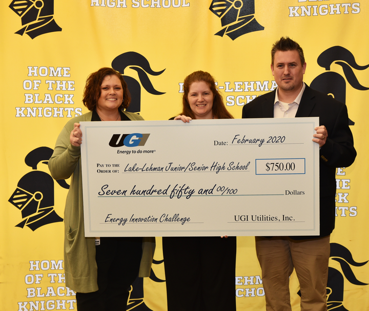 three people holding a large check