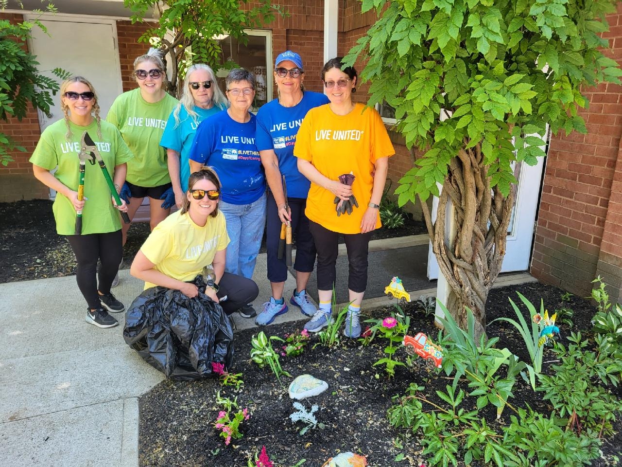 UGI employees smile in front of flower bed at Kingston Active Adult Center.