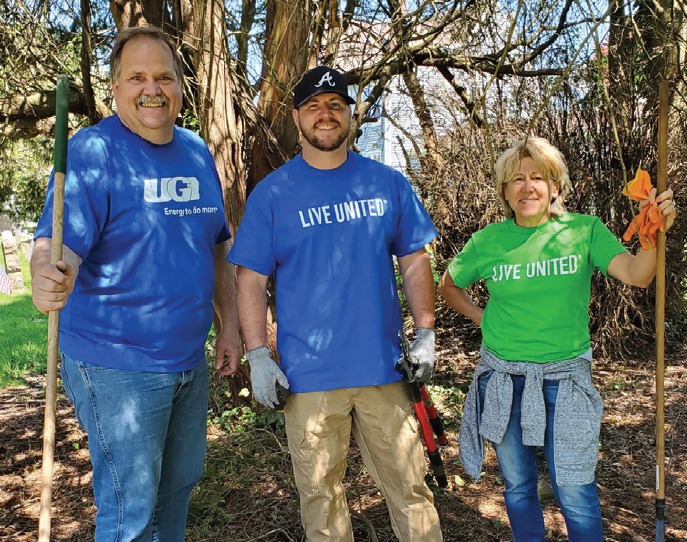 UGI employees posing for a picture while raking leaves