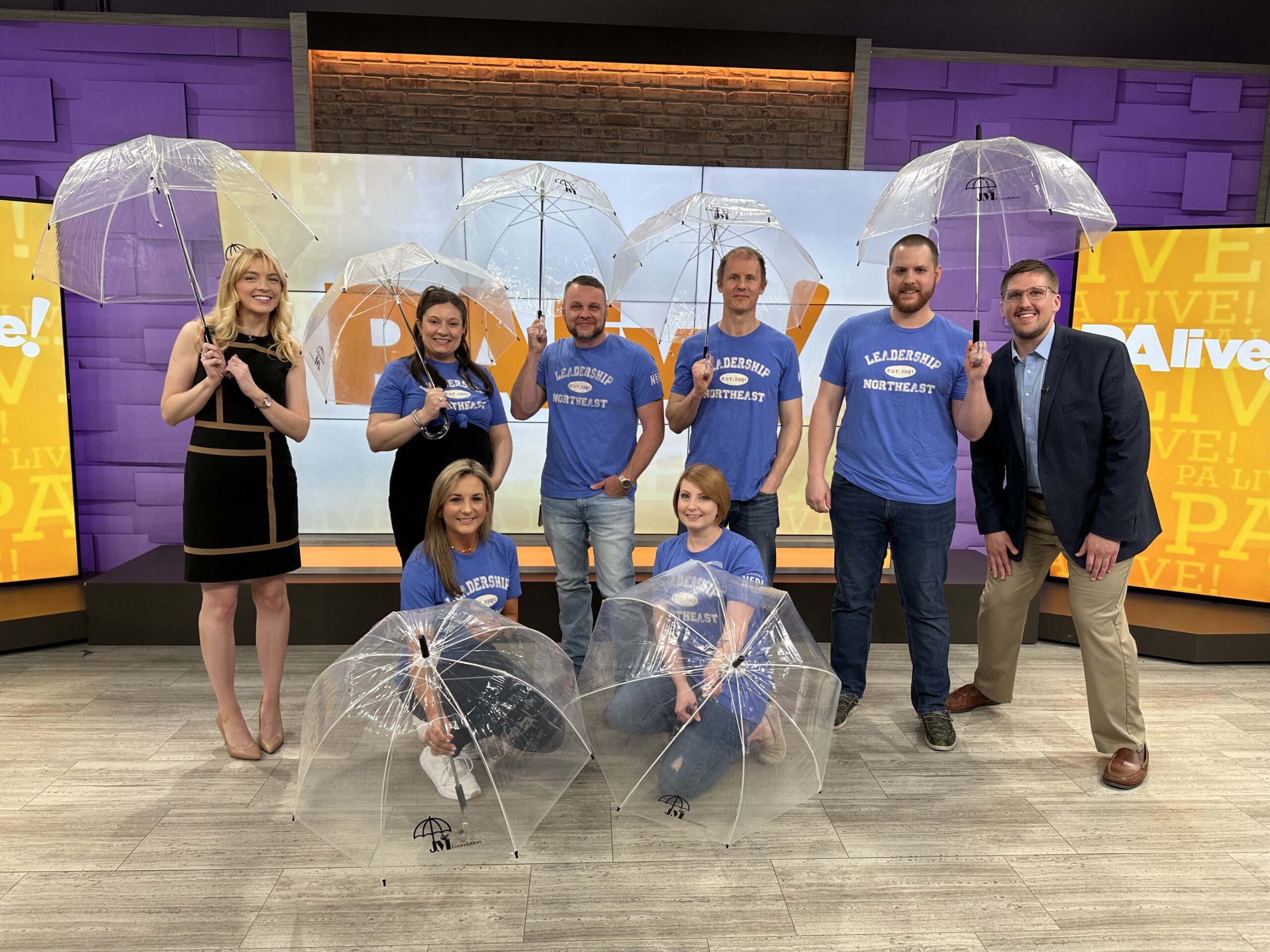 Group at TV studio holding translucent umbrellas in support of Mental Health Awareness Month.