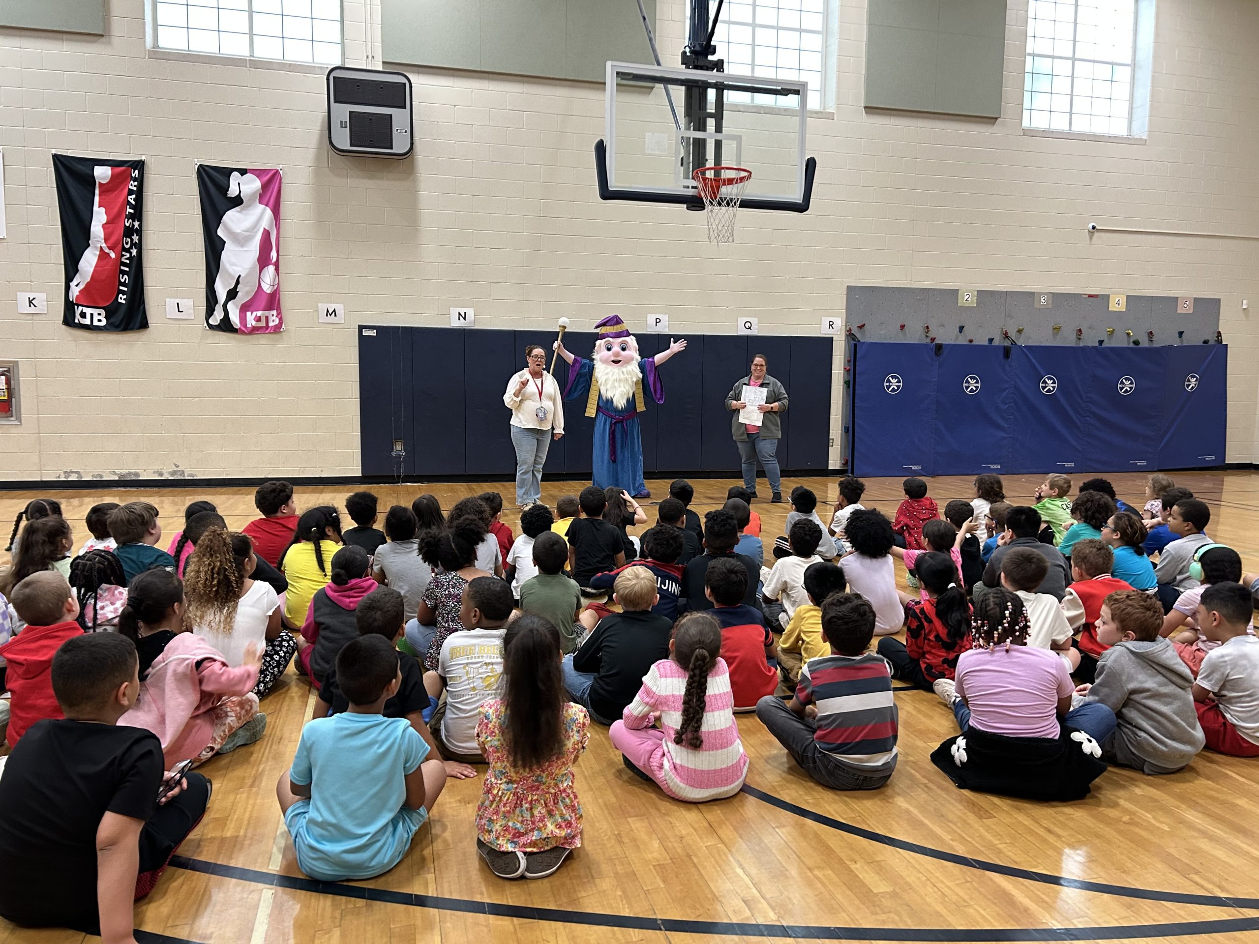 Reading Wizard stands in front of students at assembly.