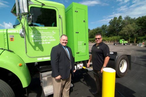 Two men standing by truck that is being pumped with natural gas