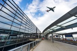 airplane flying by airport building