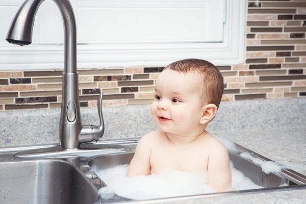 Baby bathing in sink powered by gas hot water heaters