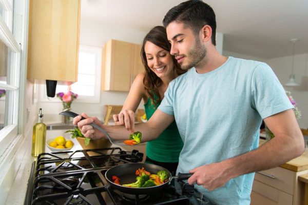 Couple cooking dinner over natural gas stoves