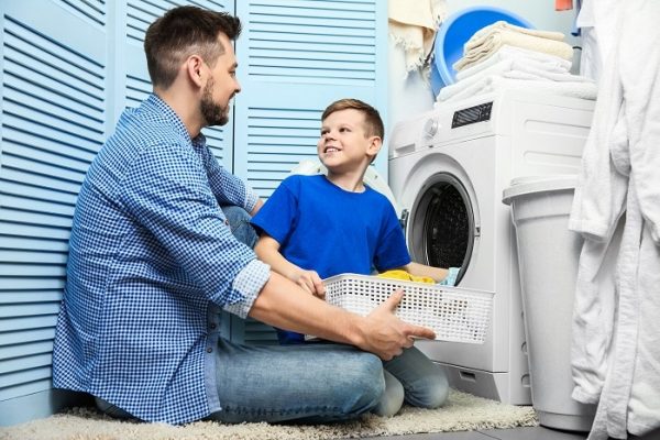 Father and son doing laundry from natural gas dryers