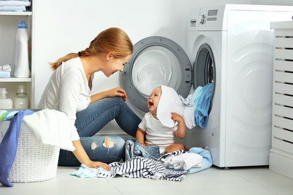 Baby and mother folding clothes by the natural gas dryer
