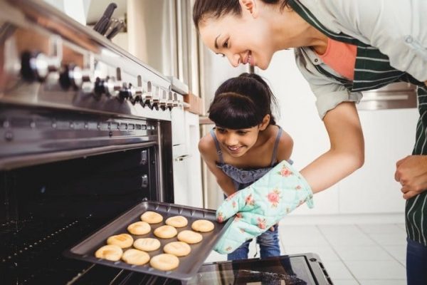 Mother and daughter baking cookies in natural gas ovens
